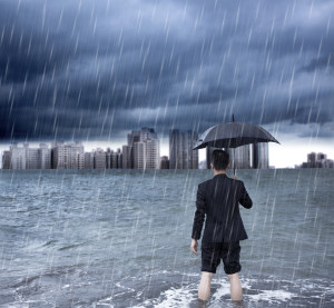 business man holding an umbrella and standing with cloudburst background