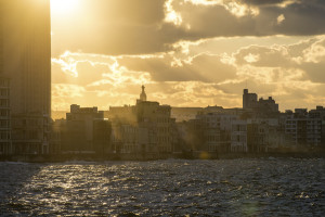 The sun begins to set in the Cuban capital Havana, seen here from the Malecón, the broad esplanade and seawall which stretches for 8 km (5 miles) along the coast.The silhouette of the Virgin Mary is visible atop a church tower.